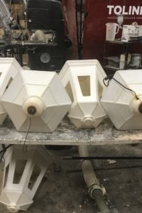 A table full of white lanterns with various spots and stains awaits sanding and painting.