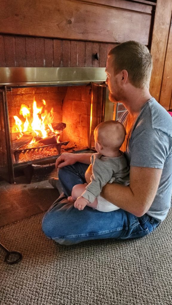 Steve Tolin holds his new daughter, Eloise, in front of the fireplace in his home. 